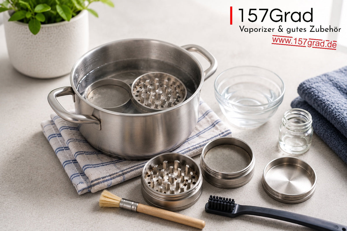 Grinder in Einzelteilen neben einem Topf mit heißem Wasser und Reinigungsbürsten