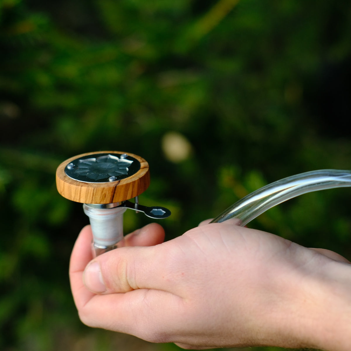 INHALE Lotus aus Olivenholz in der Hand im Wald