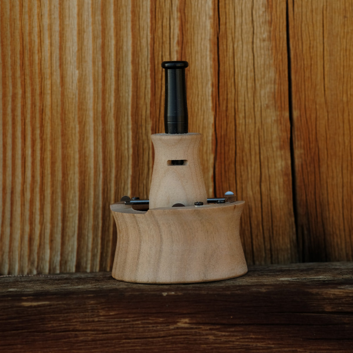 INHALE Vapman Click aus Olivenholz vor einer Holzwand
